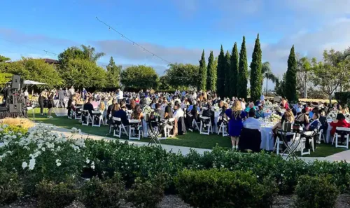 Elegant outdoor wedding reception in San Diego with round guest tables, white floral centerpieces, and lush garden surroundings.