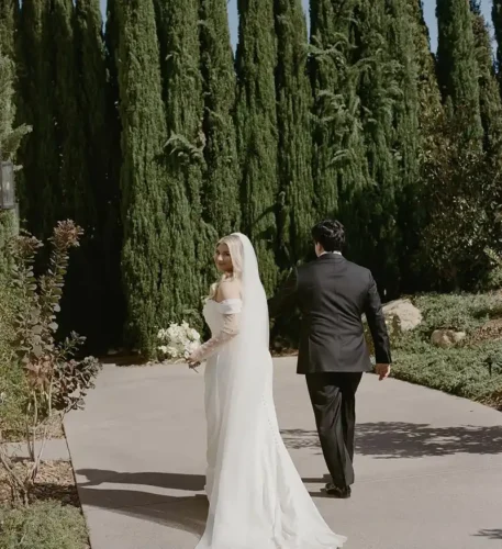 Bride and groom walking through a beautiful tree-lined wedding venue in California.