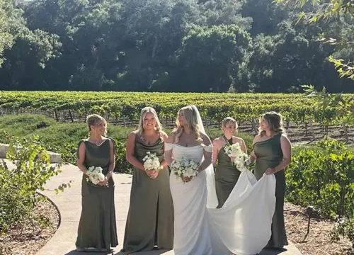 Bride with bridesmaids holding white bouquets at a scenic vineyard wedding in Santa Barbara, California.