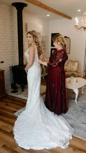 Bride getting ready with assistance fastening her wedding dress before a luxury wedding in Malibu, California.