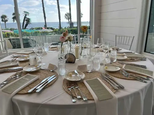 Round wedding reception table with ocean view and woven placemats in Huntington Beach California.