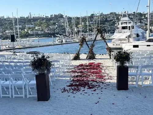 Luxury waterfront wedding ceremony with a rose petal aisle and floral arch overlooking the marina in Dana Point, California.