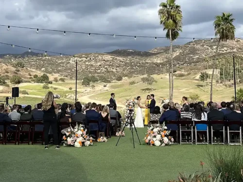 Luxury outdoor wedding ceremony with floral aisle arrangements and scenic mountain views in Temecula, California.