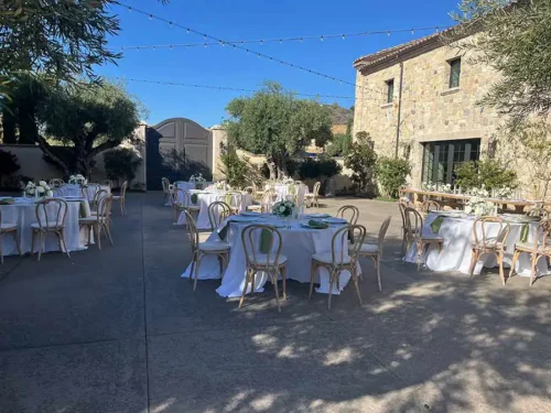 Elegant outdoor wedding reception setup with round tables, white linens, and string lights at a luxury San Diego wedding venue.