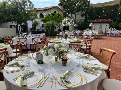 Elegant outdoor wedding reception with floral centerpieces, round tables, and string lights at a luxury venue in Newport Beach, California.