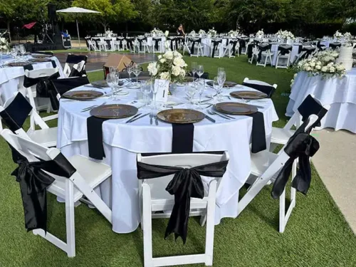 Elegant outdoor wedding reception with white tables, black chair sashes, and floral centerpieces in Temecula Wine Country, California.