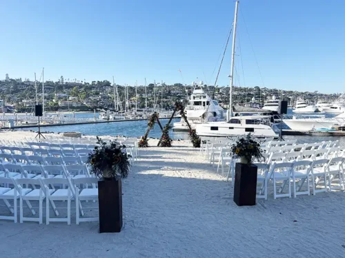 Luxury waterfront wedding ceremony setup with a floral arch overlooking the marina in Newport Beach, California.
