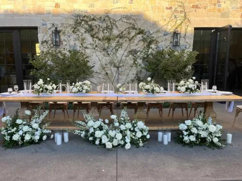 Elegant wedding head table with white floral arrangements, candles, and modern décor at a luxury outdoor wedding venue in San Diego, California.