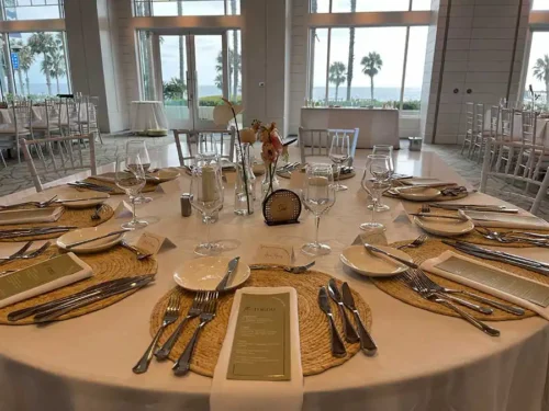 Elegant wedding reception table with woven charger plates, custom menus, glassware, and coastal-inspired décor at a luxury wedding venue in Santa Monica, California.