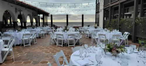 Elegant outdoor wedding reception setup with ocean views and string lights in California.