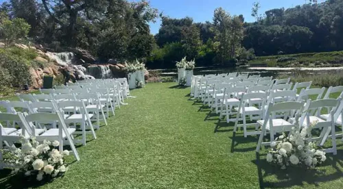 Elegant outdoor lakeside wedding ceremony with white chairs and floral arrangements in Santa Monica, California.