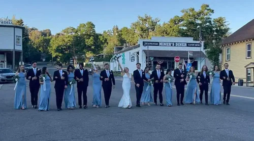 Bride, groom, bridesmaids, and groomsmen posing together for a joyful wedding party photo in Laguna Beach, California.