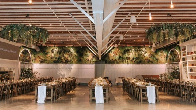 Flora The Venue, a downtown San Diego wedding venue featuring elegant banquet tables, greenery, floral décor, and a modern wood-beam ceiling.