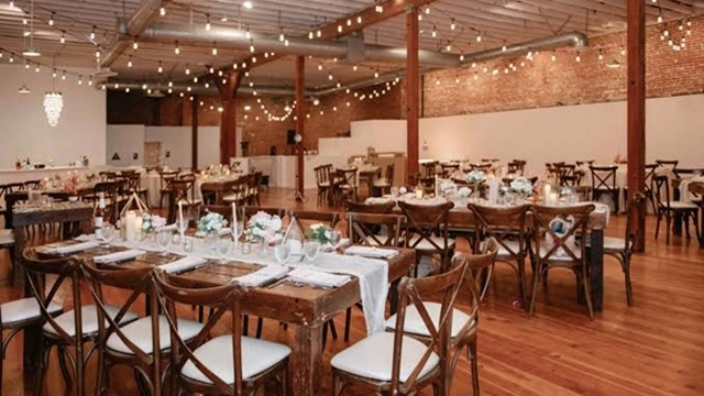 Rustic reception setup inside The Sinclair on G Street, featuring exposed brick walls, string lighting, polished wood floors, and elegantly arranged dining tables for a downtown San Diego wedding.