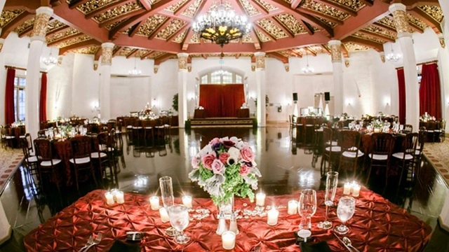 The Don Room at El Cortez, a historic downtown San Diego wedding venue with elegant banquet tables, floral centerpieces, chandeliers, and ornate ceiling décor.
