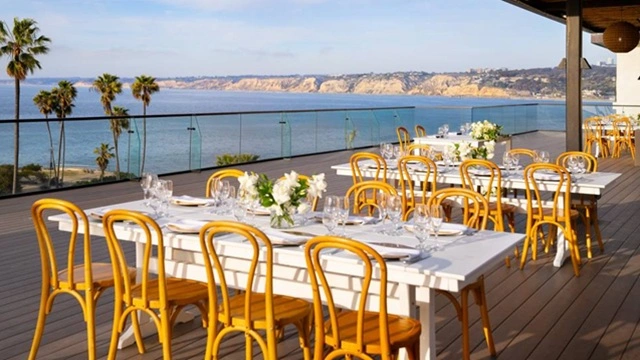 Elegant outdoor wedding reception overlooking the Pacific Ocean at a luxury coastal venue in La Jolla, San Diego, featuring beautifully arranged dining tables and panoramic waterfront views.